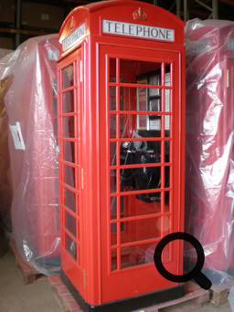 Rote Telefonzelle mit Glasfenstern, stehend in einem Innenraum.